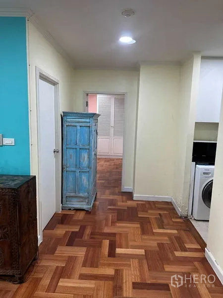 公寓 出租或出售在Bangkok - 走廊通向卧室，蓝色柜子并可见厨房。