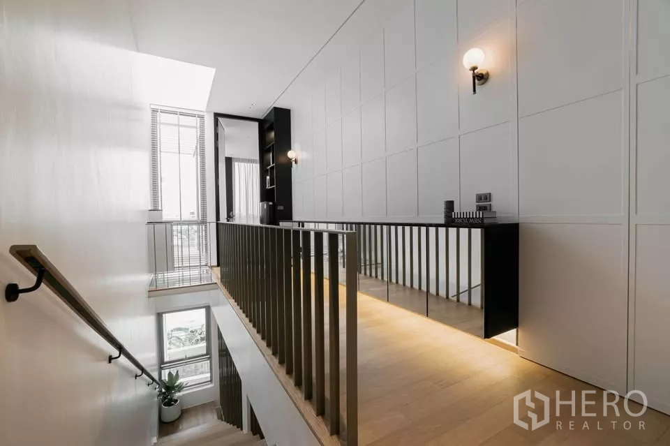 Townhouse for sale in Chatuchak, Bangkok - Stair hall with tall window, panelled wall and sleek handrail.