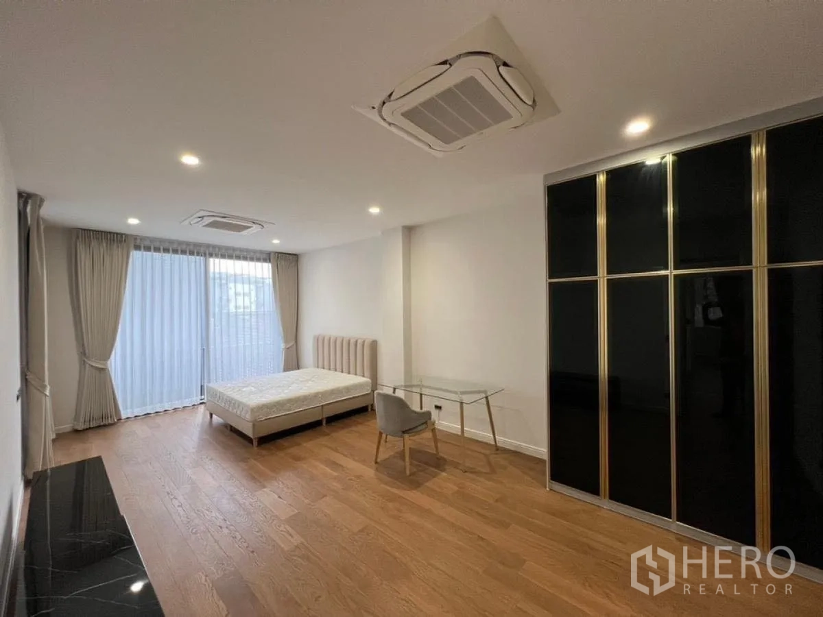 Detached House for rent in Wang Thonglang, Bangkok - Large bedroom with bed, black built-in wardrobe, and sheer curtains.