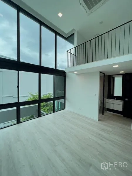 Detached House for rent or sale in Saphan Sung, Bangkok - Corner double-volume bedroom with tall windows and an ensuite vanity.