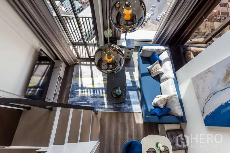 Condominium for rent - Top-down view of the double-height living room with pendant lamps and balcony.