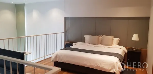 公寓 出租在Khlong Toei, Bangkok - 夹层卧室，设大床、床头柜与栏杆，可俯瞰客厅。