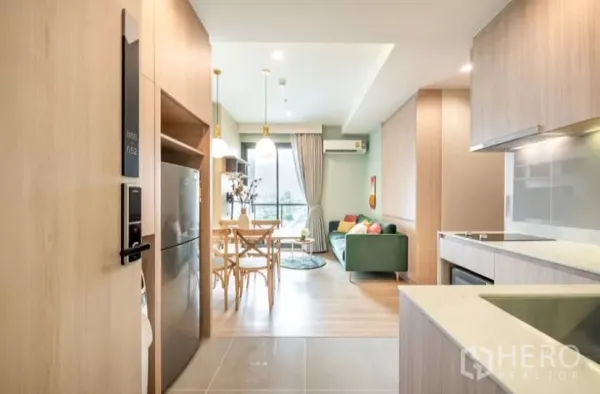 Condominium for rent in Chatuchak, Bangkok - Entry corridor leading to the light-filled living room and balcony beside a modern kitchenette.