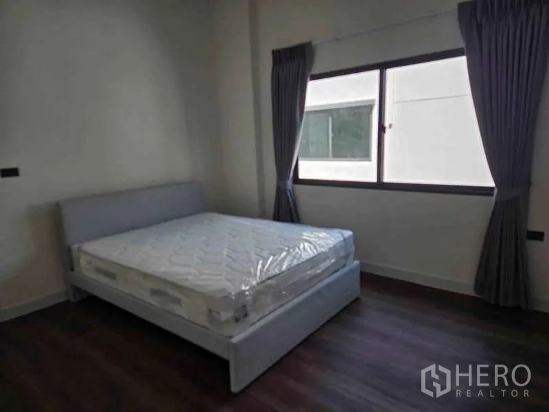 Detached House for rent in Bang Phli, Samut Prakan - Guest bedroom with bed, dark curtains and a large window.