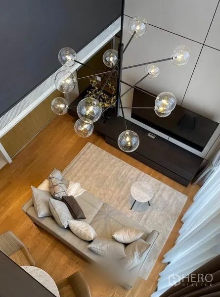 Condominium for rent in Khlong Toei, Bangkok - Top-down view of the living room showing chandelier, sofa and light wood flooring.