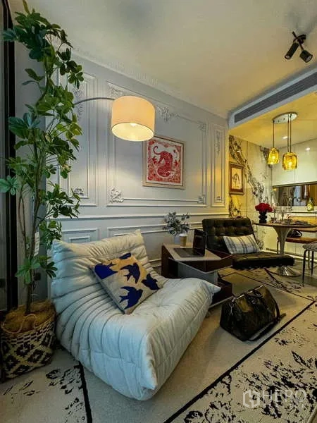 Condominium for rent - Living area with potted tree, soft armchair and view into the open kitchen and dining.
