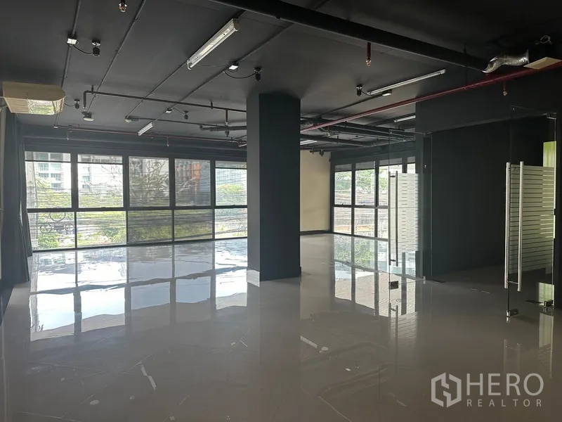 办公空间 出租在Khlong Toei, Bangkok - 开放式办公区，落地窗与亮面瓷砖地面，外露吊顶。