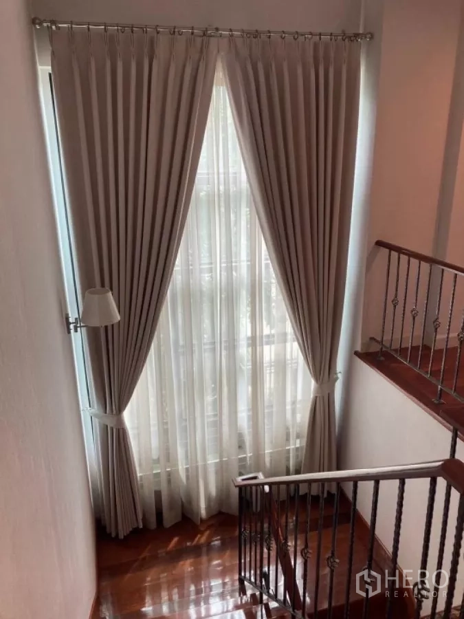 Detached House for rent in Mueang Nonthaburi, Nonthaburi - Stairwell featuring a tall window dressed with drapes and wooden steps.