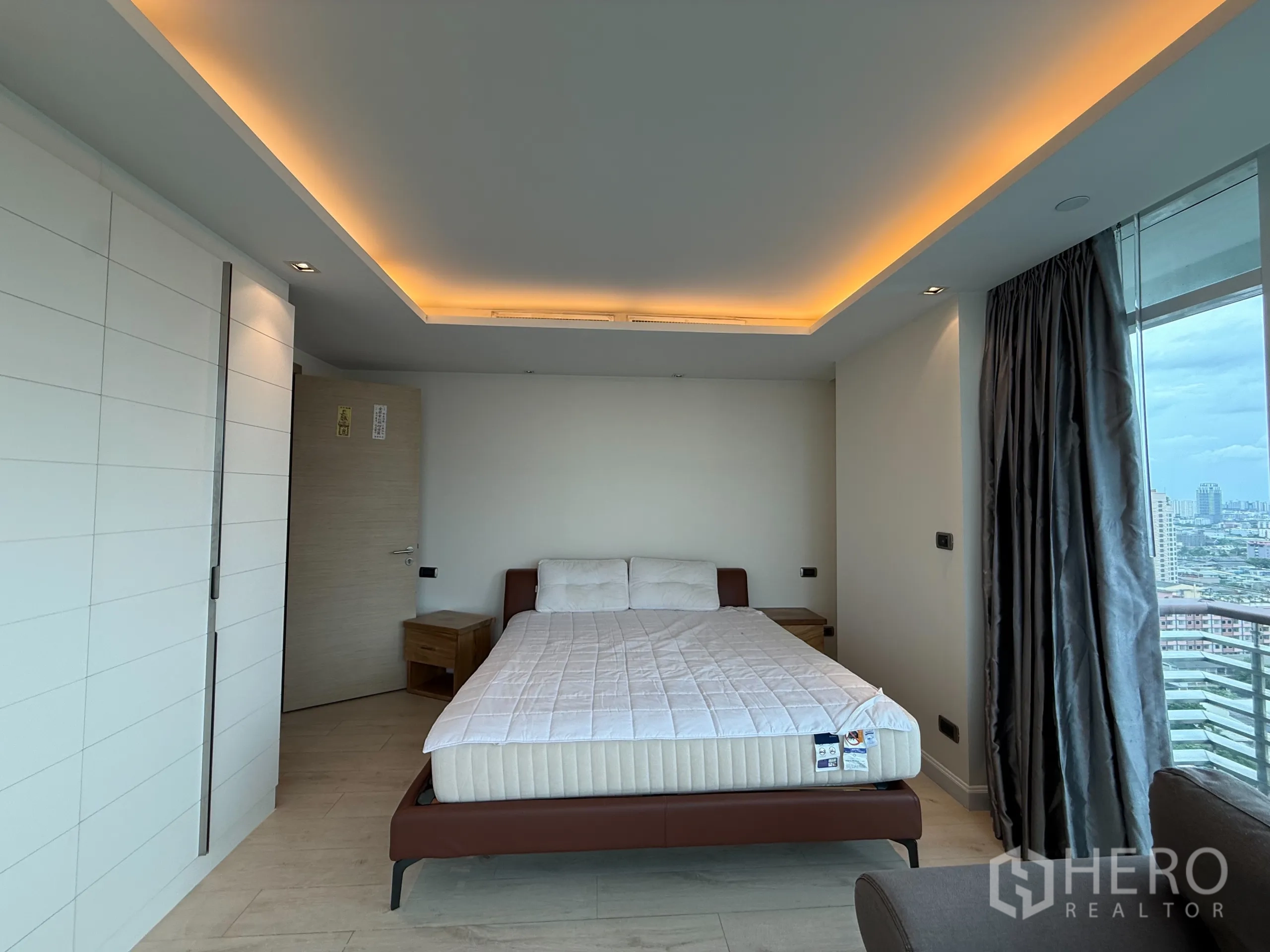 Condominium for rent in Phaya Thai, Bangkok - Corner bedroom with cove lighting, upholstered bed and panoramic windows to the skyline.