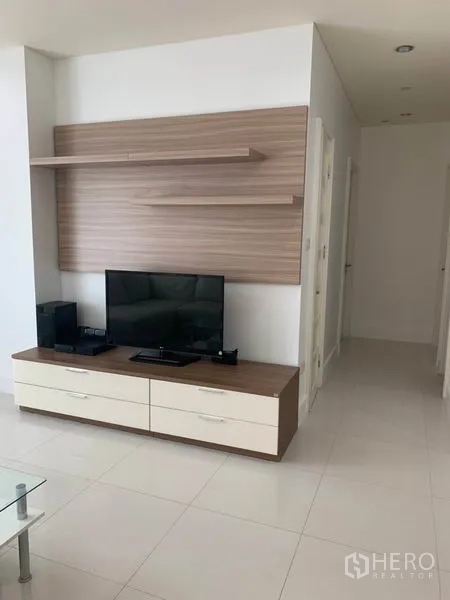 Condominium for rent in Khlong Toei, Bangkok - Modern media wall with floating shelves and a flat-screen TV facing the open-plan living area.