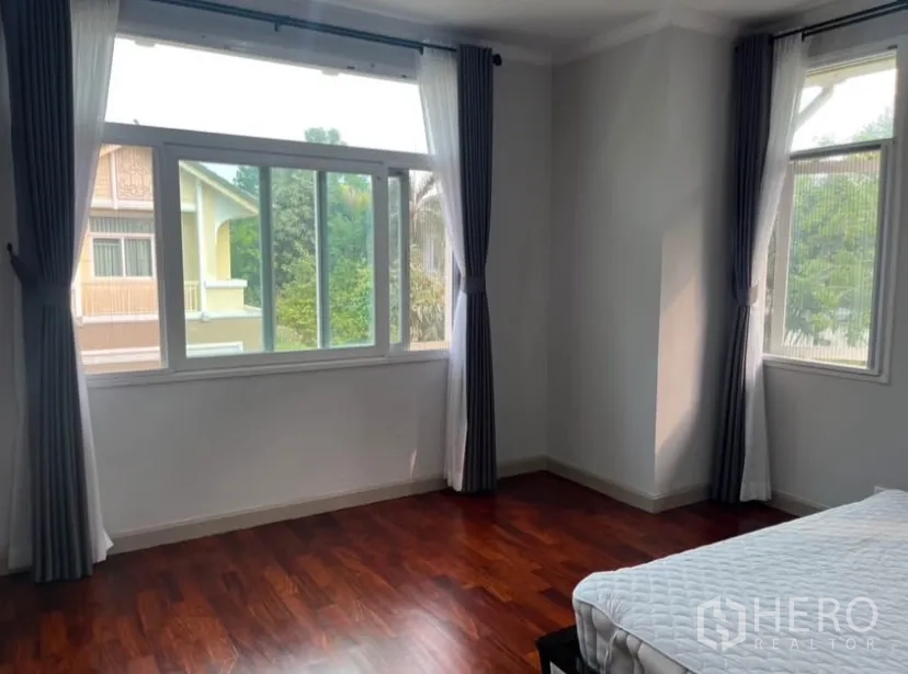 Detached House for rent or sale in Lat Phrao, Bangkok - Master bedroom corner windows with garden view and curtains.