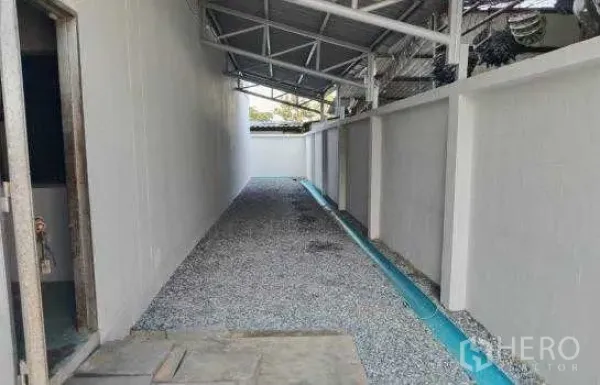 Warehouse for rent or sale in Prawet, Bangkok - Covered side lane beside the warehouse with gravel surface and drainage channel.