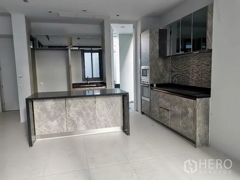 Detached House for sale in Wang Thonglang, Bangkok - Kitchen and pantry area with an island bench and a window to the utility zone.