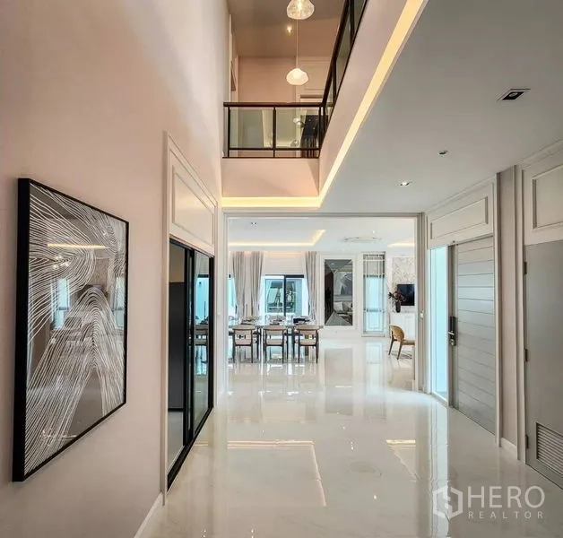独立式住宅 出售在Bang Phli, Samut Prakan - 挑高中庭，亮面地坪与玻璃栏杆，望向起居区