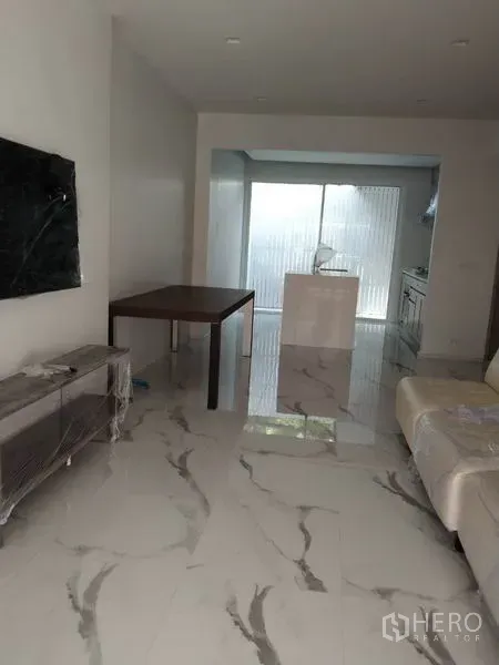 Townhouse for rent in Yan Nawa, Bangkok - Open‑plan living area with marble‑look flooring leading to a bright kitchen.
