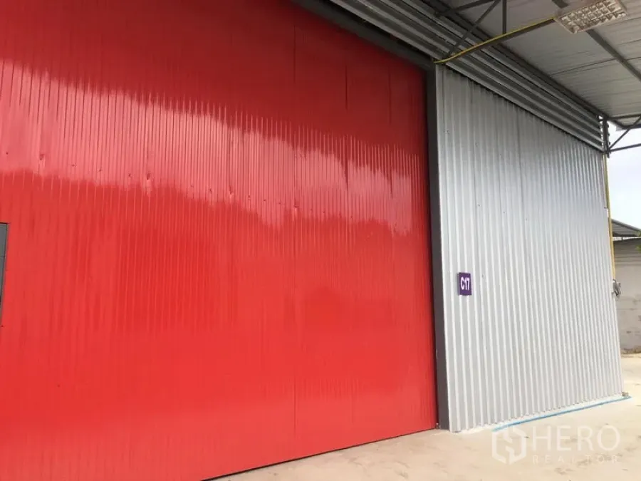 Warehouse for rent in Prawet, Bangkok - Exterior view of warehouse with large red sliding steel door and covered loading apron.