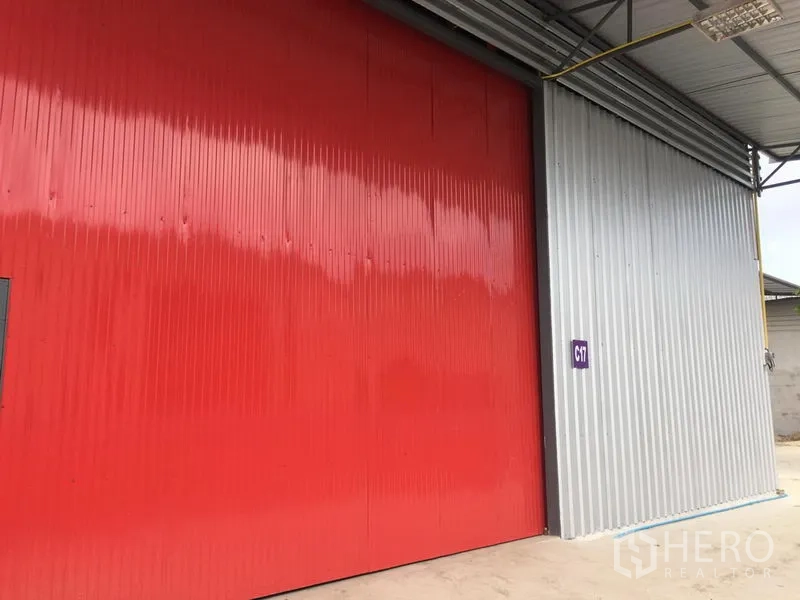 Warehouse for rent in Prawet, Bangkok - Exterior view of warehouse with large red sliding steel door and covered loading apron.