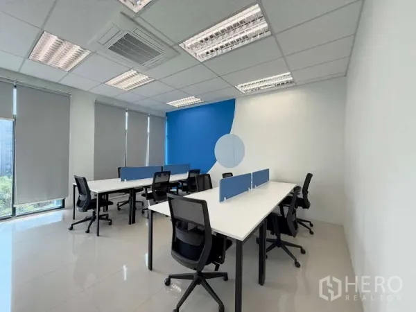 Office Space for rent in Huai Khwang, Bangkok - Private office layout with two bench desks, blue accent wall, roller blinds and city-green views.
