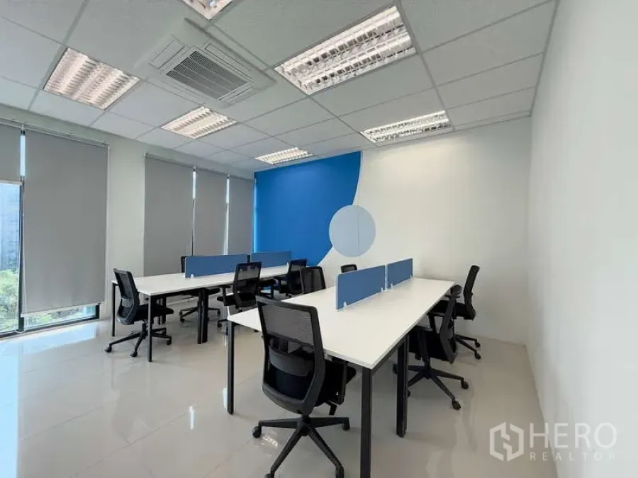 Office Space for rent in Huai Khwang, Bangkok - Private office layout with two bench desks, blue accent wall, roller blinds and city-green views.