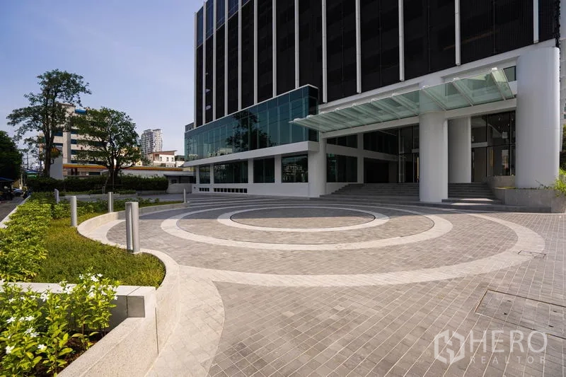 办公空间 出租在Bang Rak, Bangkok - 带雨棚的下客区，圆形车道与绿化入口。
