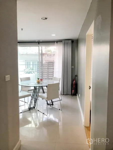 Condominium for rent or sale in Khlong Toei, Bangkok - Hallway view to dining nook with round glass table beside sliding doors.