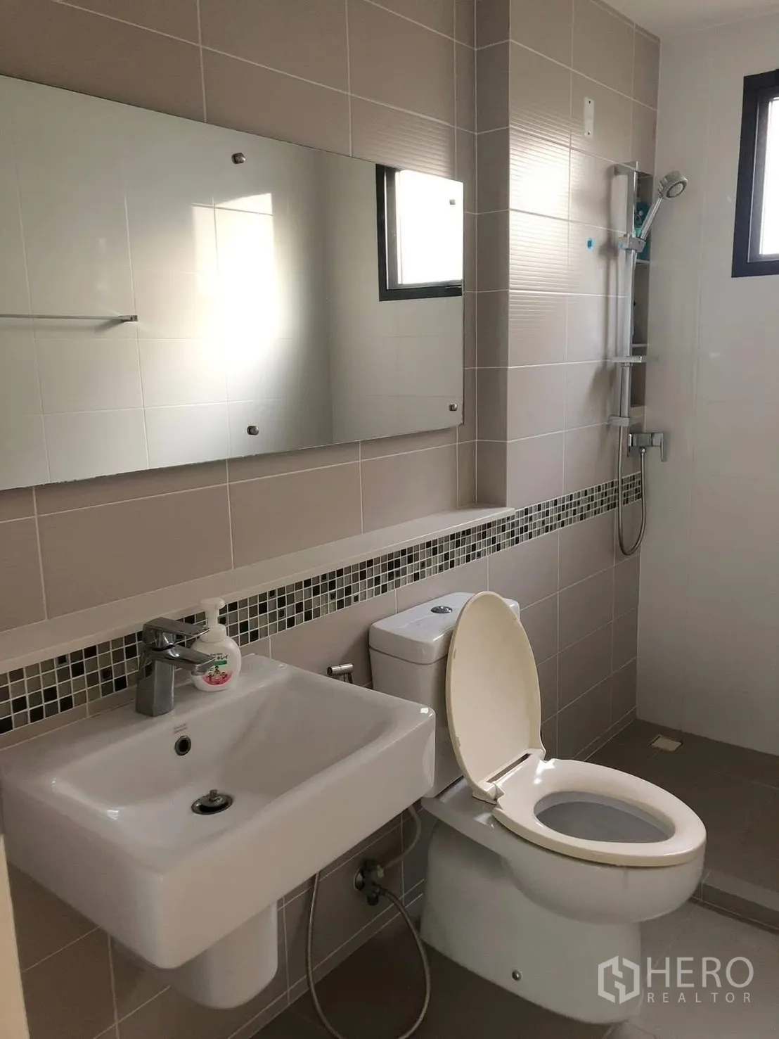Detached House for rent in Prawet, Bangkok - Modern bathroom with tiled walls, vanity, toilet and a walk-in shower with handheld head.