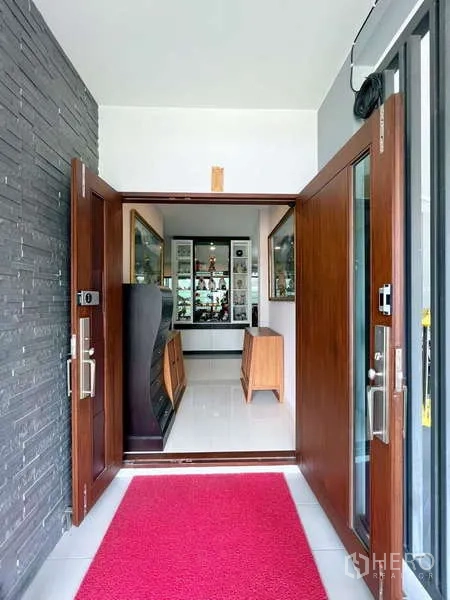 独立式住宅 出售在Prawet, Bangkok - 宽大的木制入户门，通向明亮门厅与玻璃展示柜、亮面地砖。