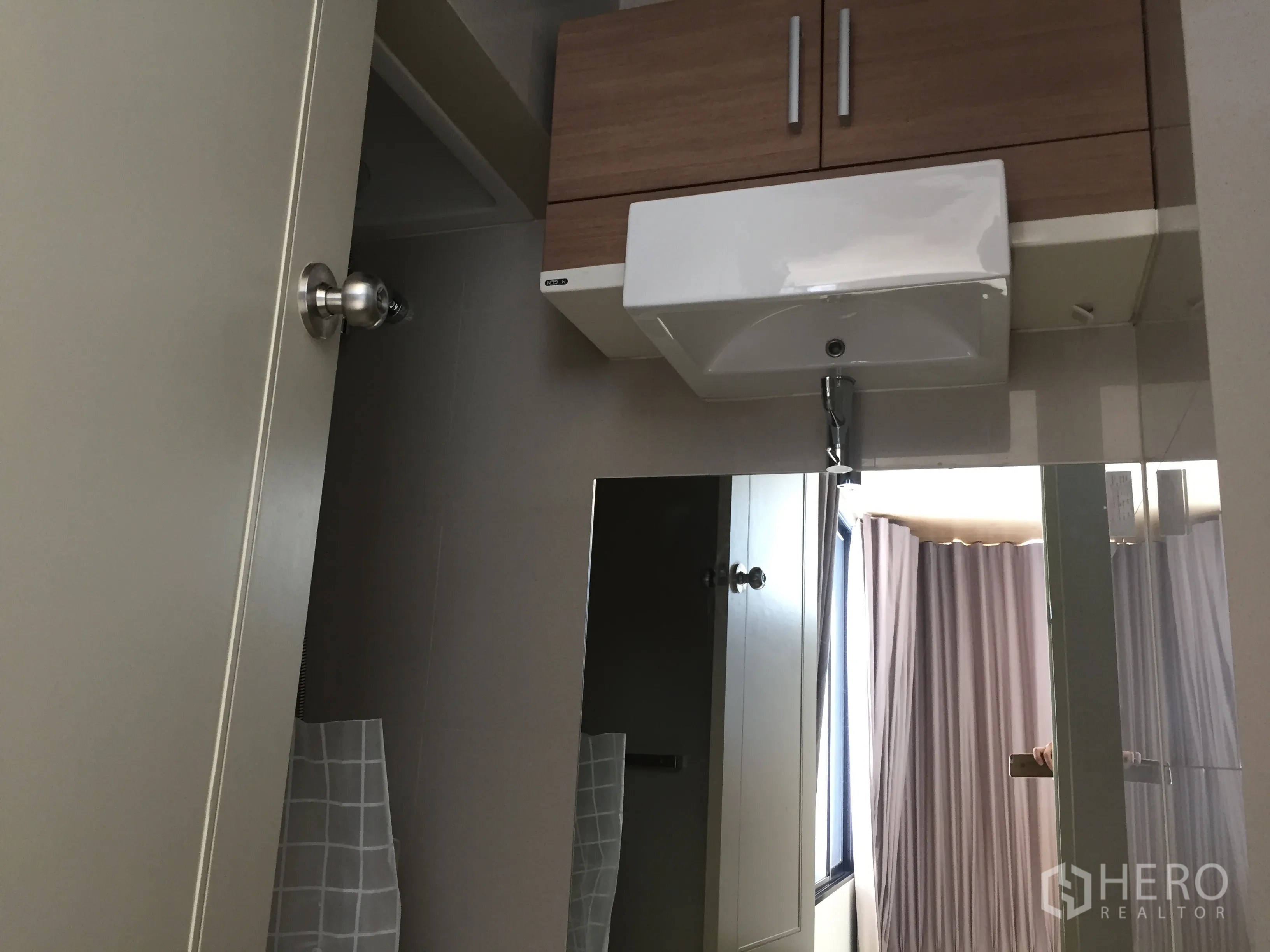 Condominium for rent or sale in Watthana, Bangkok - Compact bathroom with wall cabinet, large mirror and white basin.