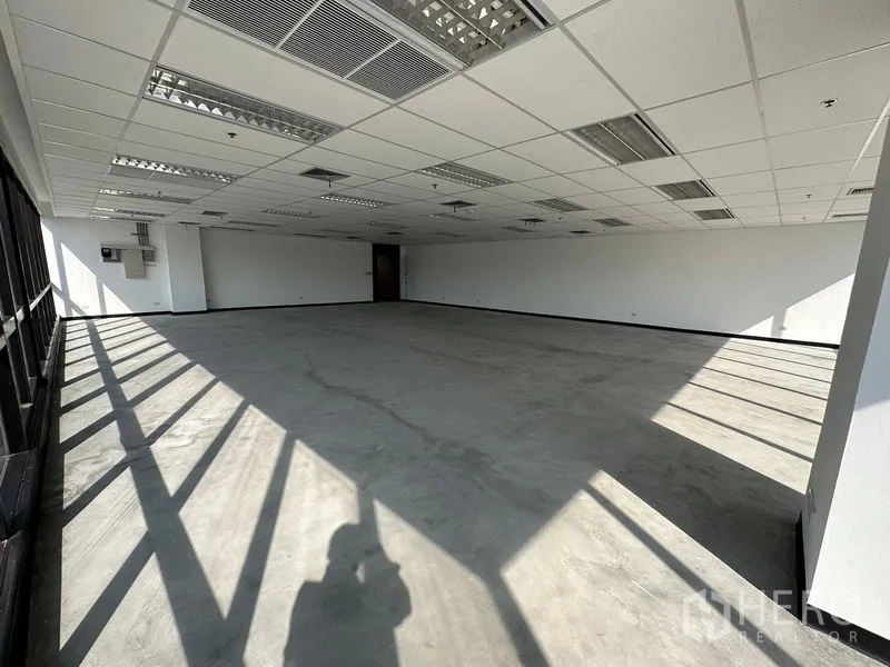 办公空间 出租在Watthana, Bangkok - 大型未配家具的办公室，整面窗墙，日光在地面形成影子。