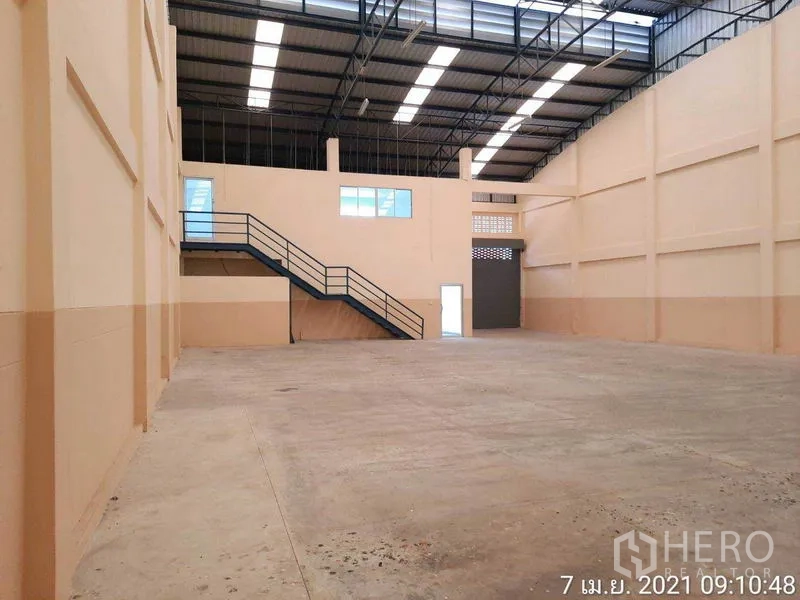 Factory for rent in Bang Bua Thong, Nonthaburi - Warehouse view showing steel truss roof, mezzanine staircase and loading door.