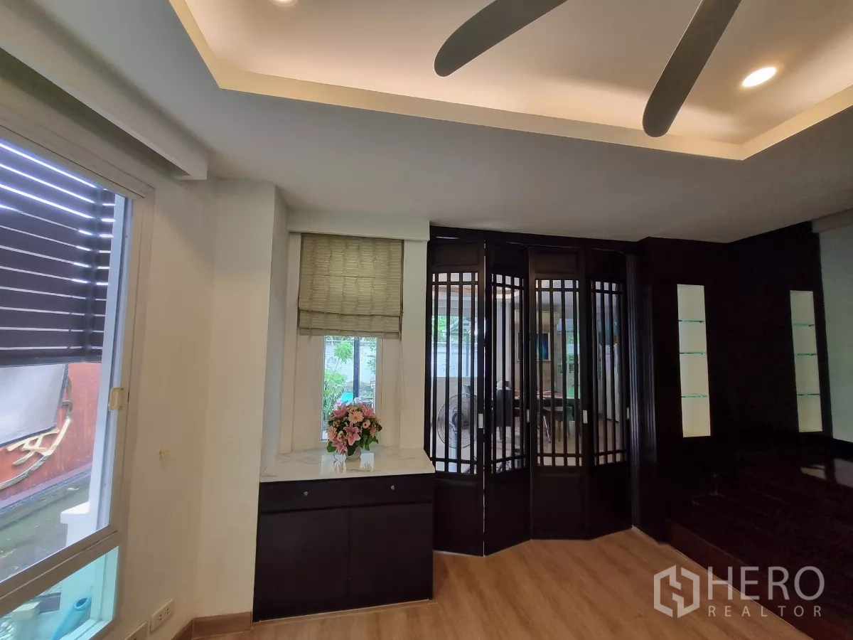 独立式住宅 出租在Bang Kapi, Bangkok - 现代客厅，木地板、吊扇与折叠玻璃隔断。