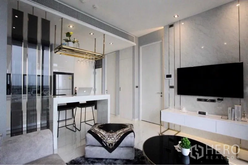 Condominium for rent in Bangkok - Living room TV wall with mounted screen and sleek white media console beside breakfast bar.