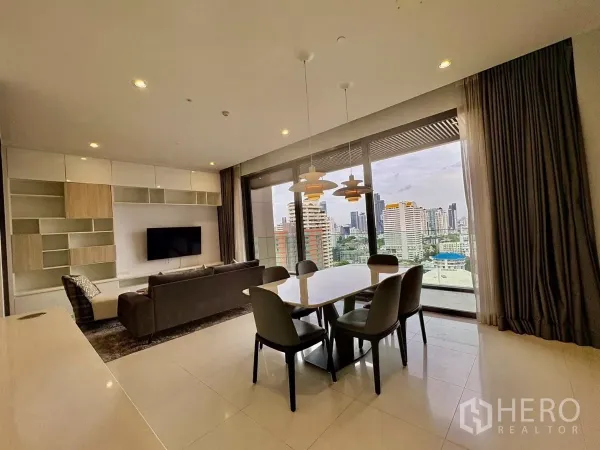 公寓 出租在Watthana, Bangkok - 电视墙、沙发与餐桌，通过推拉玻璃门俯瞰城市景色。