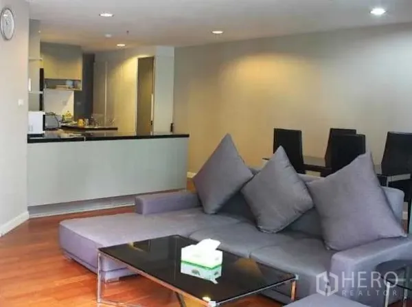 คอนโด ให้เช่าในHuai Khwang, Bangkok - ห้องนั่งเล่นเปิดโล่ง โซฟาเข้ามุมสีเทา โต๊ะกระจก และพื้นไม้ ใกล้ครัวสมัยใหม่