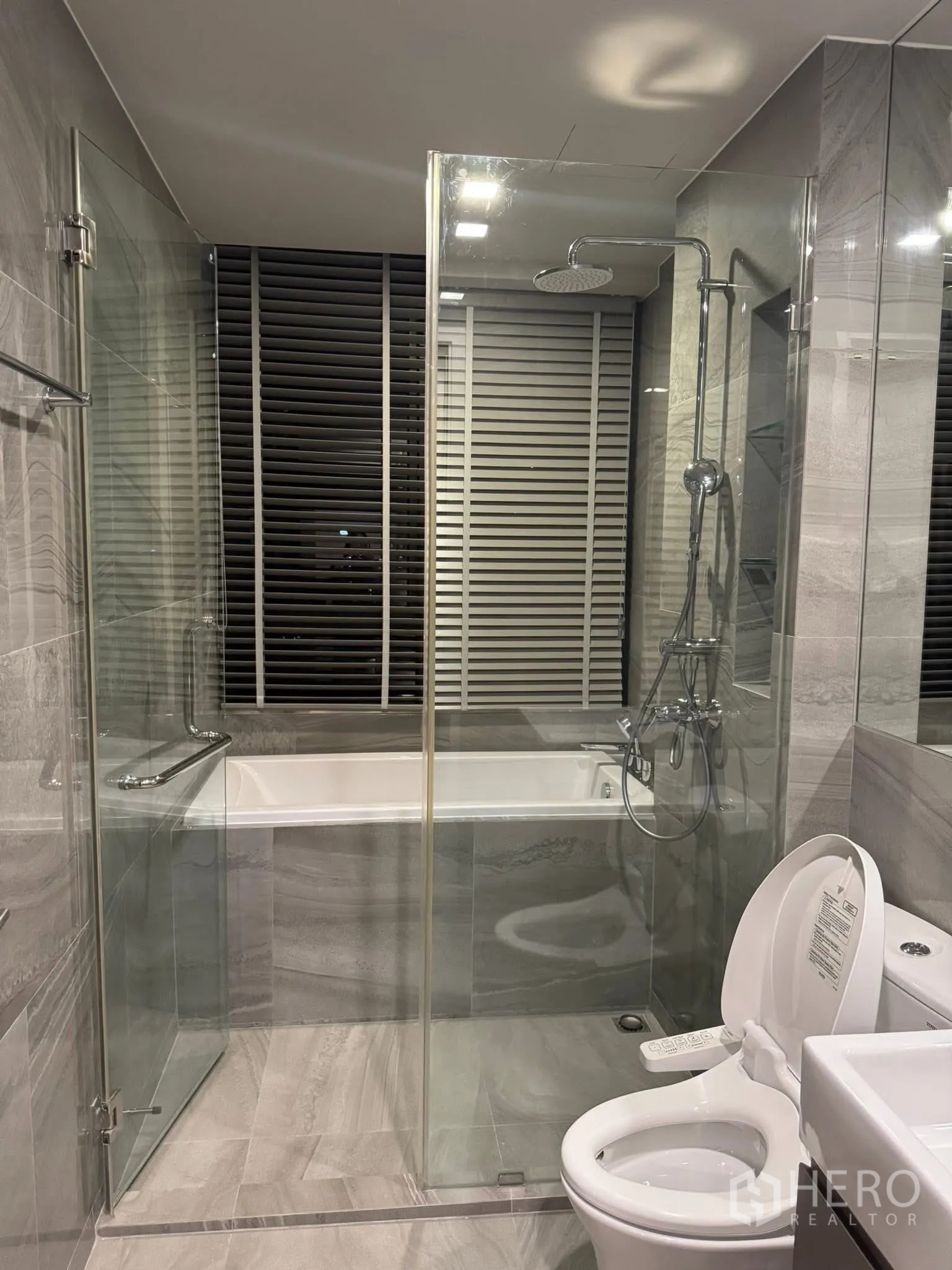 Condominium for rent in Khlong Toei, Bangkok - Contemporary bathroom with glass shower, bathtub and bidet toilet.