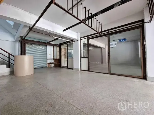 Office Space for rent in Din Daeng, Bangkok - Spacious open-plan office floor with glass partitions, exposed metal frames, a roller shutter and polished concrete flooring.