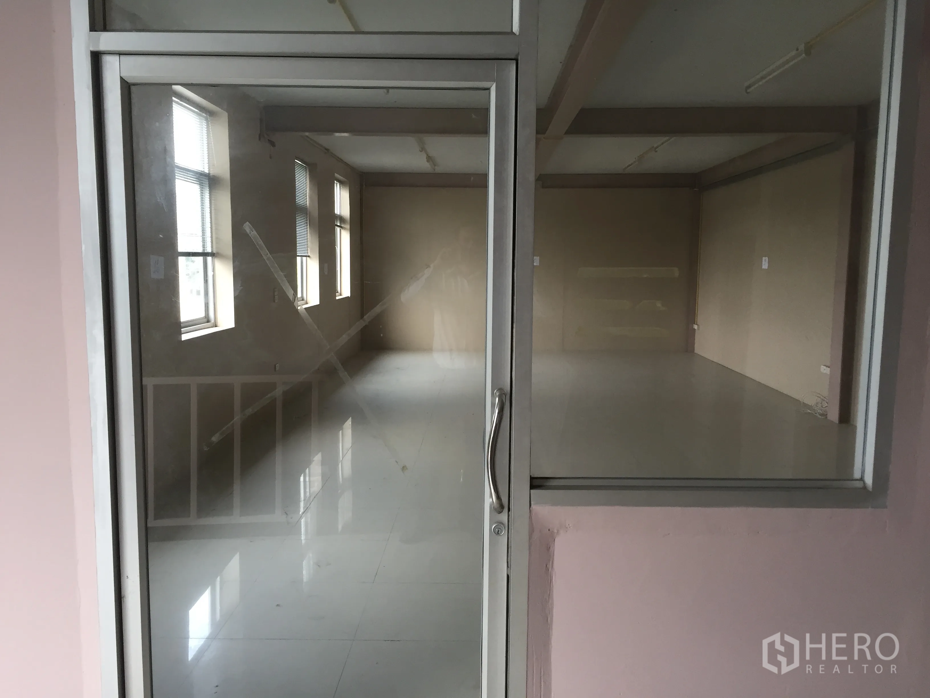 Factory for rent in Lam Luk Ka, Pathum Thani - Glass-fronted mezzanine office with tiled flooring and windows for natural light.