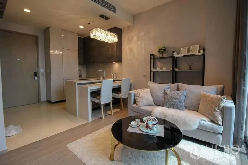 公寓 出售在Watthana, Bangkok - 开放式客餐厅，灰色沙发、圆形茶几，岛台上方水晶吊灯。