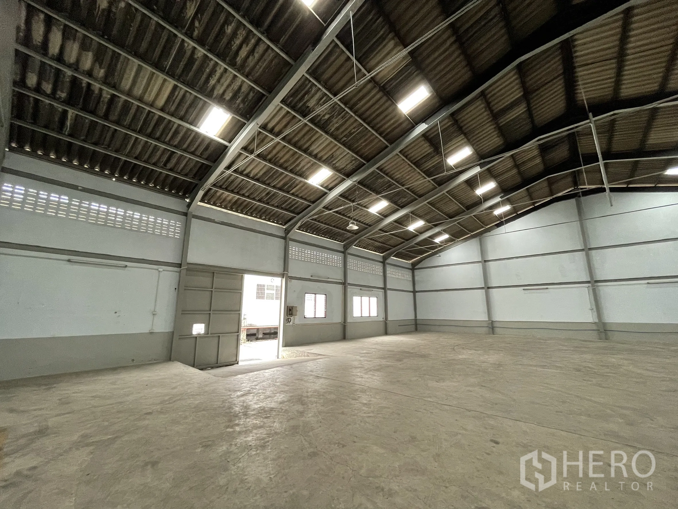 Factory for rent in Mueang Samut Prakan, Samut Prakan - Interior view showing side door, windows, and open clear floor space.
