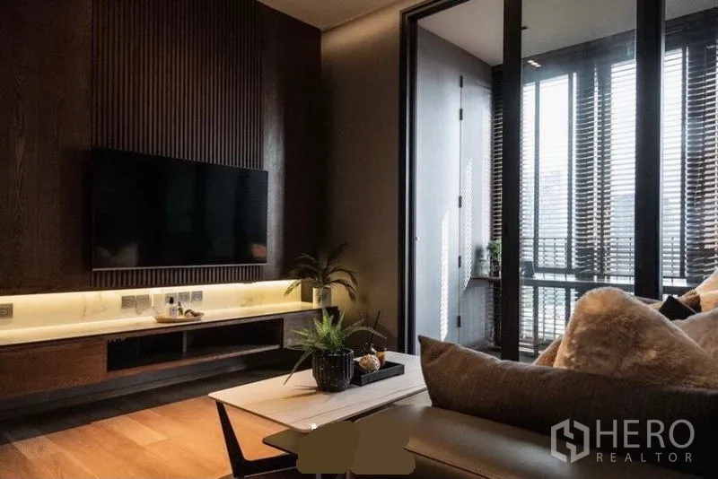 Condominium for rent in Khlong Toei, Bangkok - Built-in TV wall with ribbed wood paneling and LED shelf lighting beside full-height glass doors.