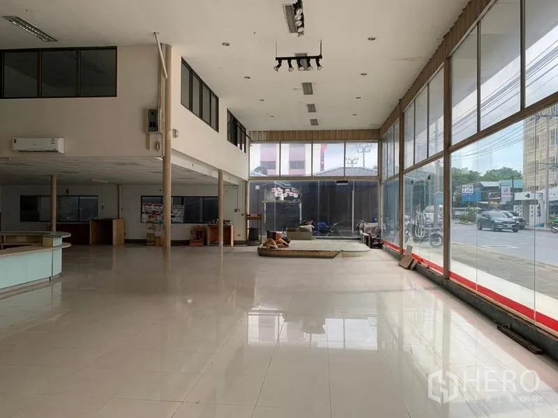 Warehouse for rent in Bang Khen, Bangkok - Spacious open-plan showroom with floor-to-ceiling windows, glossy tiled flooring and mezzanine office space.