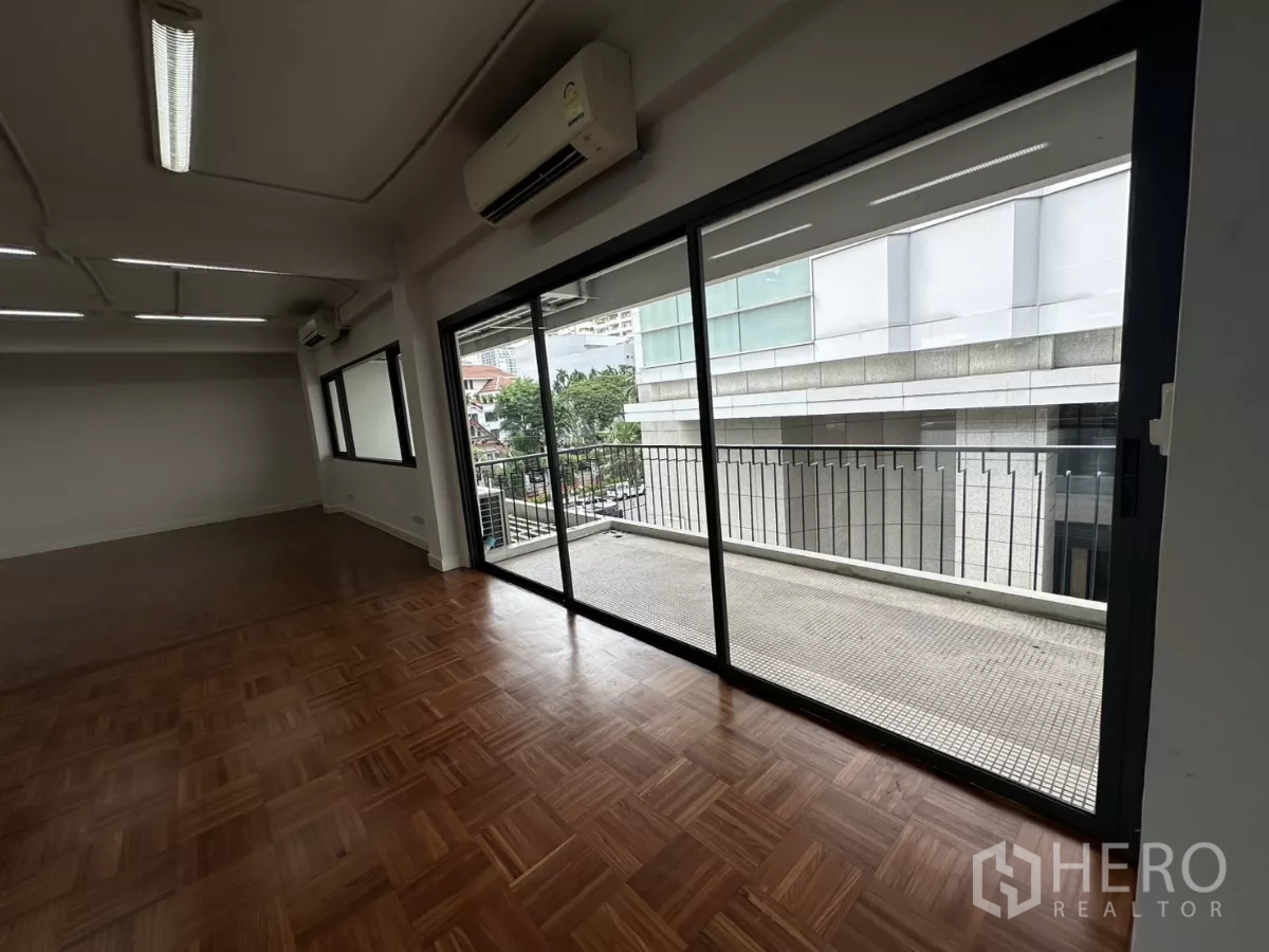 สำนักงาน ให้เช่าในWatthana, Bangkok - มุมออฟฟิศที่มีประตูกระจกบานเลื่อนไปยังระเบียง มองเห็นอาคารข้างเคียง.