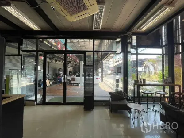 Warehouse for rent in Lat Phrao, Bangkok - Glass‑walled office and waiting area with seating, air‑conditioning and a view into the workshop.