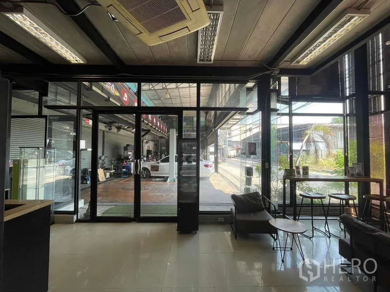 Warehouse for rent in Lat Phrao, Bangkok - Glass‑walled office and waiting area with seating, air‑conditioning and a view into the workshop.