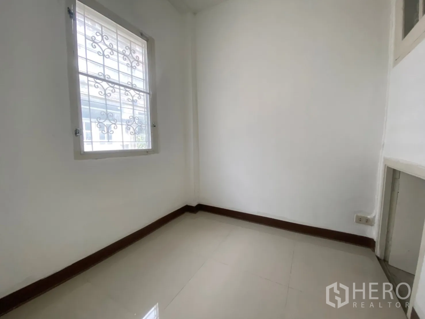 Townhouse for rent in Watthana, Bangkok - Compact maid’s room or storage space with grilled window and tiled floor.