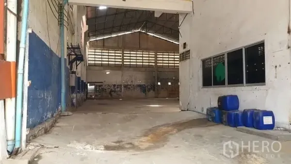 Warehouse for rent in Phra Samut Chedi, Samut Prakan - Open warehouse entry view showing the high roof, ventilation panels and clear floor space for staging or storage.