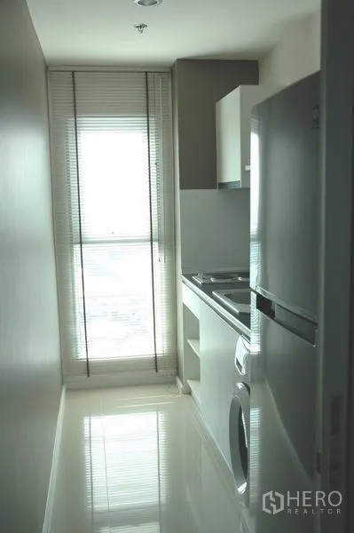 Condominium for sale in Khlong Toei, Bangkok - Slimline separate kitchen with tall fridge, sink, washing machine and floor-to-ceiling window.