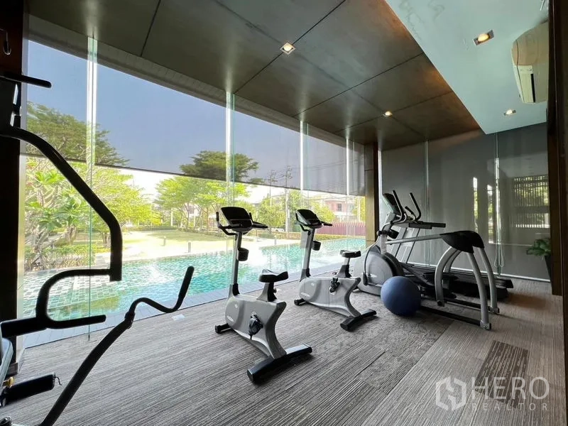 Detached House for rent or sale in Bang Khen, Bangkok - Glass-walled fitness room with cardio equipment overlooking the pool.