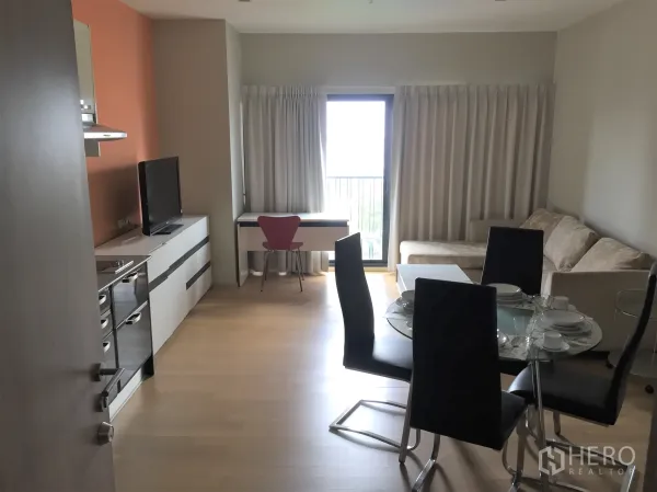 公寓 出租在Watthana, Bangkok - 开放式客餐厅，配一字型厨房、玻璃餐桌、沙发与通往阳台的落地门