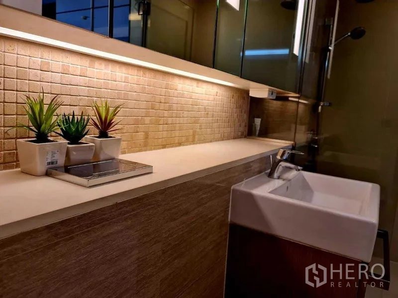 Condominium for rent in Watthana, Bangkok - Close-up of bathroom vanity with under-cabinet lighting and decorative plants.
